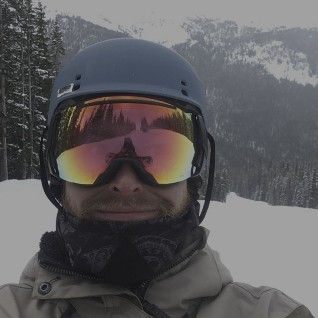 Standing alone on a ski trail in front of trees and mountains.